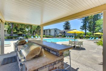 BBQ Area at Pool with Chairs, Tables and Patio Umbrellas at Renaissance Park Apartments, Davis